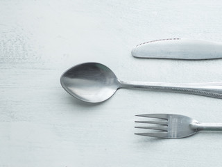 Bunch of Forks, Spoons and Knives Mixed on a Roughly Painted White Background