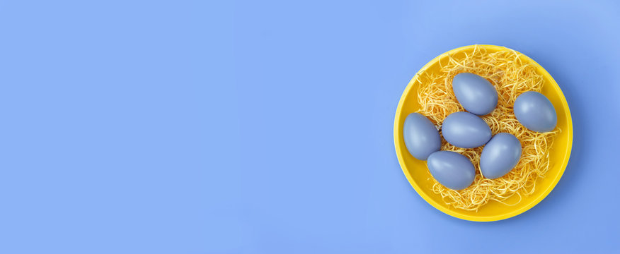 Top view of yellow plate with blue Easter eggs