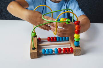 Child plays Montessori game. Kid collects wooden toy sorter. Multicolored geometric   circles and...