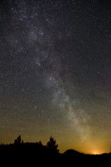 USA, California, Modoc County, Lava Beds National Monument. Milky Way Galaxy stretches into the night sky above the glow from Klamath Falls, OR.