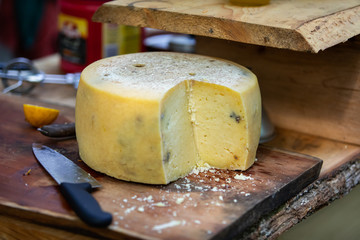 A close up shot on a truckle, wheel, of traditional farmhouse cheddar cheese on a rustic wooden...