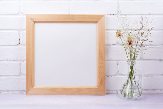 Wooden square frame mockup with grass in the glass jug