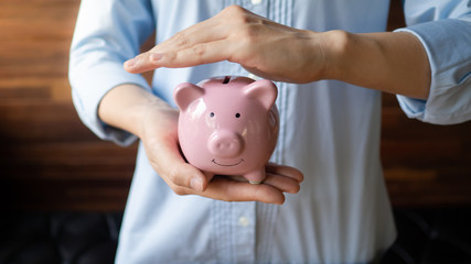 A woman is protecting piggy bank, saving protection concept
