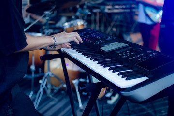 Musician playing on the keyboard synthesizer piano keys. Musician plays a musical instrument on the concert stage - obrazy, fototapety, plakaty