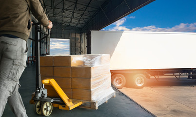 Worker courier unloading cargo pallet shipment goods, his using hand pallet jack load into a truck, Road freight transport, Warehouse industrial delivery shipment and logistics
