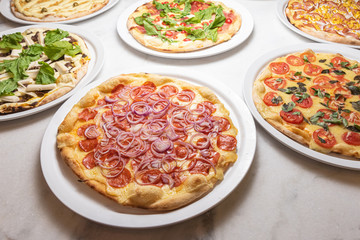 Various pizzas on the white marble table