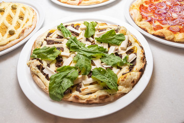 Various pizzas on the white marble table