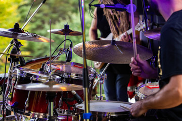 A close up detailed selective focus view of a man playing a drum kit on stage during a festival celebrating earth and alternative communities