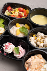 Tasty lunch in plastic containers on grey table, vertical