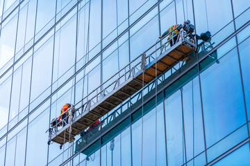 Professional high rise window cleaning service workers in gondola. Two workers use specialized...