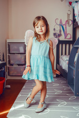 Cute adorable pretty dressed preschool girl playing a fairy princess at home. Child creativity...
