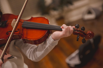 Girl practicing violin at home in pajamas