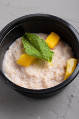 barley porridge with dried yellow fruits in black container, closeup food