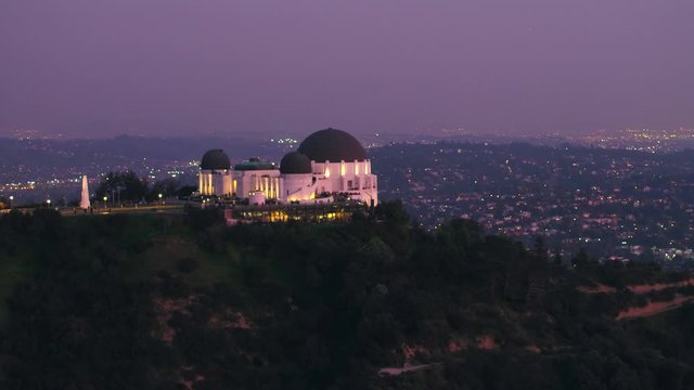 Aerial, rising, drone shot, tilting towards the Griffith Observatory, at dusk, in Griffith park, Los Angeles, California, USA
