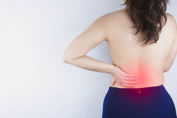 Closeup woman suffering from lower back pain with red spot. Health care and medical concept.