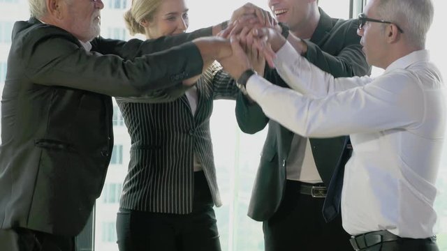 Group of business people pile of hand for startup project together with partner in the office, business man and woman happy putting hand for unity and teamwork for success in work collaboration.