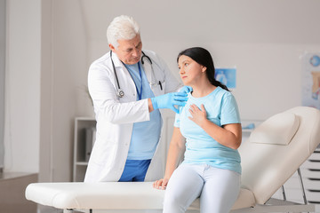 Fototapeta premium Mature male doctor working with patient in clinic