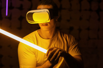 Toned portrait of African-American man with virtual reality glasses and neon lamp on dark background