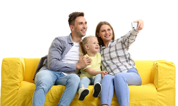 Happy Young Family Taking Selfie On Sofa Against White Background