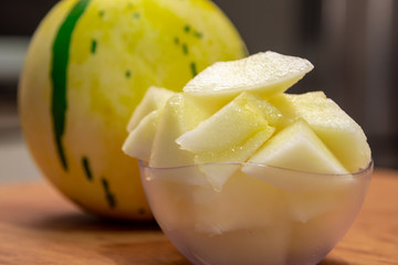 Yellow melon in pieces served in a bowl and in the background the whole fruit