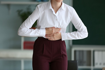 Young businesswoman suffering from abdominal pain in office