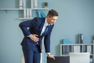 Young businessman suffering from abdominal pain in office