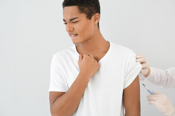 Doctor vaccinating teenage boy on white background