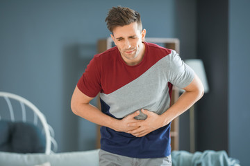 Young man suffering from abdominal pain at home