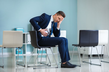 Young businessman suffering from abdominal pain in office
