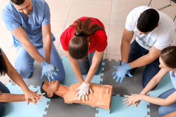 Instructors demonstrating CPR on mannequin at first aid training course