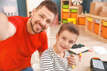 Father and his little son taking selfie while assembling furniture at home