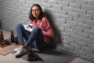 Young drunk woman near brick wall. Concept of alcoholism