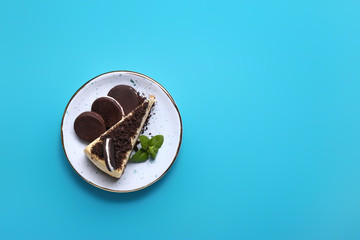 Plate with piece of tasty cheesecake and cookies on color background