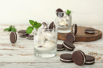 Glass with tasty ice-cream and chocolate cookies on table