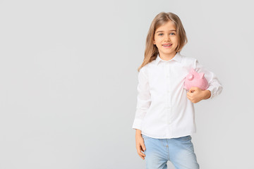 Cute girl with piggy bank on white background