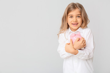 Cute girl with piggy bank on white background