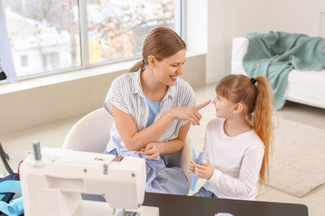 Fototapeta premium Little daughter helping her mother in tailor's workshop