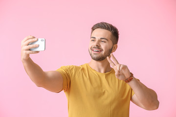 Young man taking selfie on color background