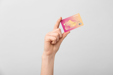 Female hand with credit card on light background