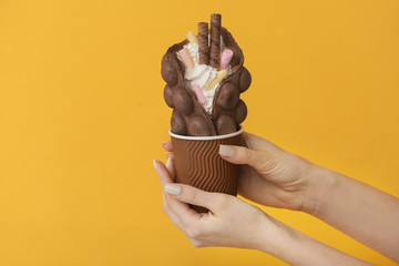 Female hands with delicious sweet bubble waffle on color background