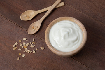 Natural homemade plain organic yogurt in wooden bowl and wood spoon on wood texture background