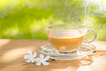 hot coffee in a coffee cup on a dark wooden table texture and natural blurred green leaf background
