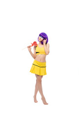 cheerful portrait of a young girl in a purple wig and yellow clothes with a heart-shaped Lollipop on a white background