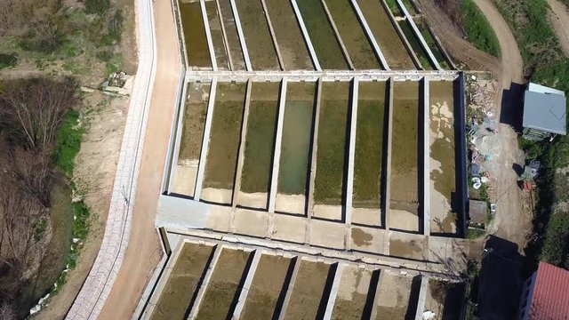 Aerial titl down shot over the enclosures of a fish farm in a river of Spain.