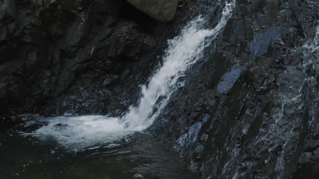 4k macro close up profile shot of cascading waterfall down small rocky cliff