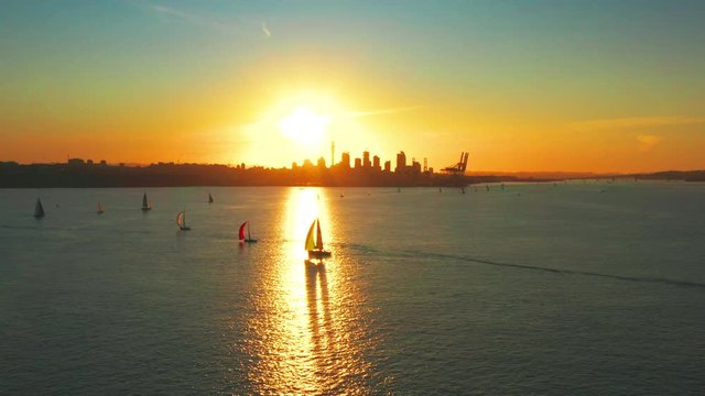 Vibrant golden sunset aerial of sailboats and Auckland city, New Zealand