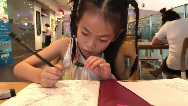 An Asian little girl is doing homework.