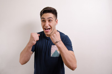 Happy young man with raised fists showing success