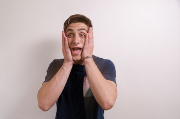 Surprised young man with hands on face