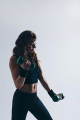 A girl in a tracksuit doing exercises with dumbbells on a white background. Healthy lifestyle concept, sports uniforms, world Cup, gym, specialized clothing, black uniforms